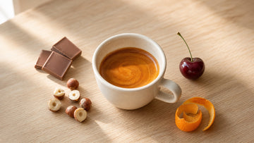 An espresso with rich crema is paired with chocolate, hazelnuts, cherry, and orange peel tasting cues.